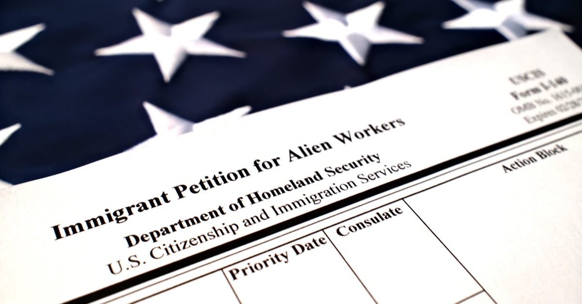 A blank I-140 immigrant petition form lying diagonally over a United States flag with white stars visible.