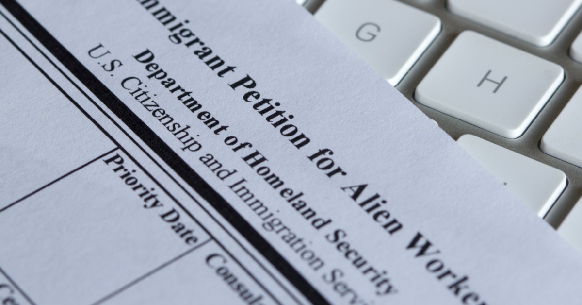 A blank I-140 immigrant petition form lying diagonally over white keyboard keys with gray trim on the right side.