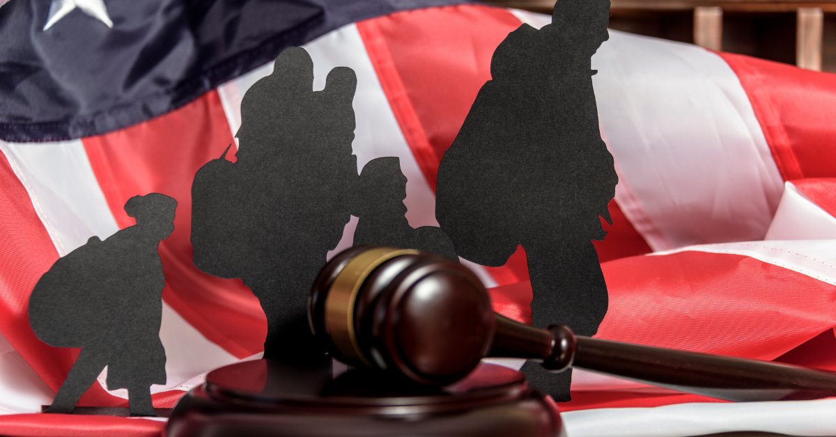 Paper silhouettes of people standing near a wooden gavel placed in front of a folded American flag cloth.