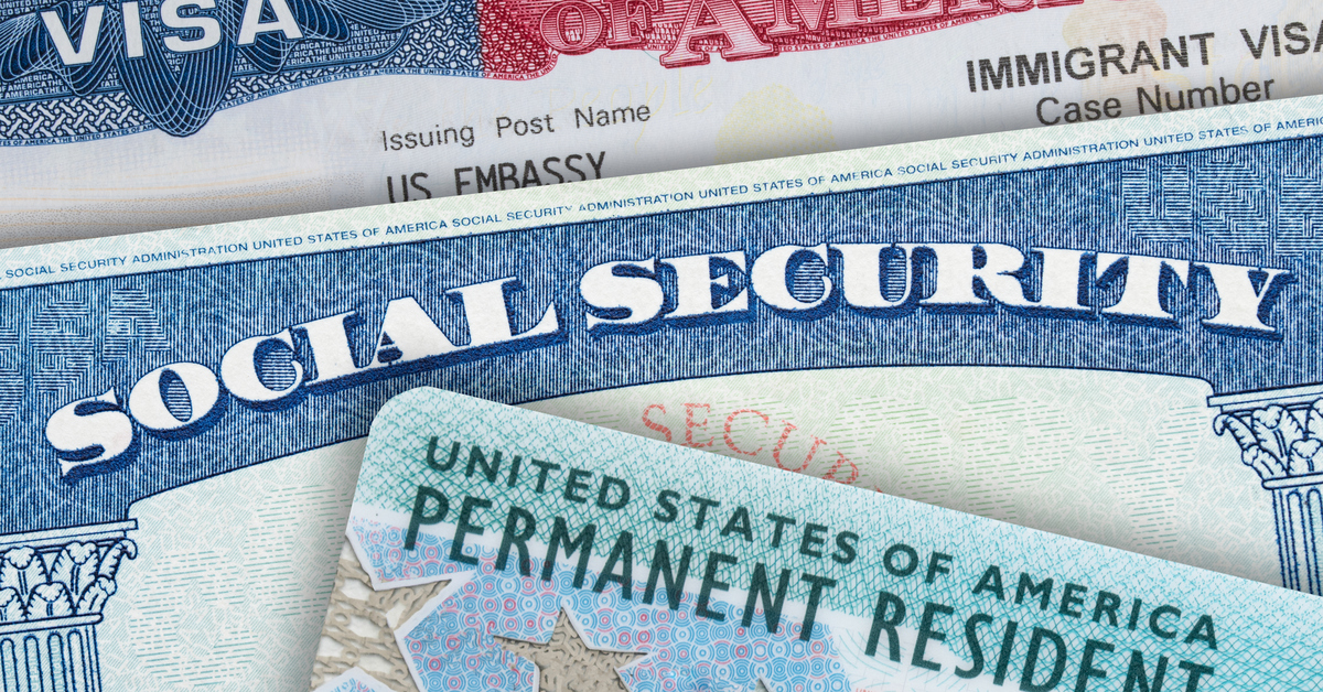 A close-up view of a United States visa card, social security card, and permanent resident card overlapping one another.