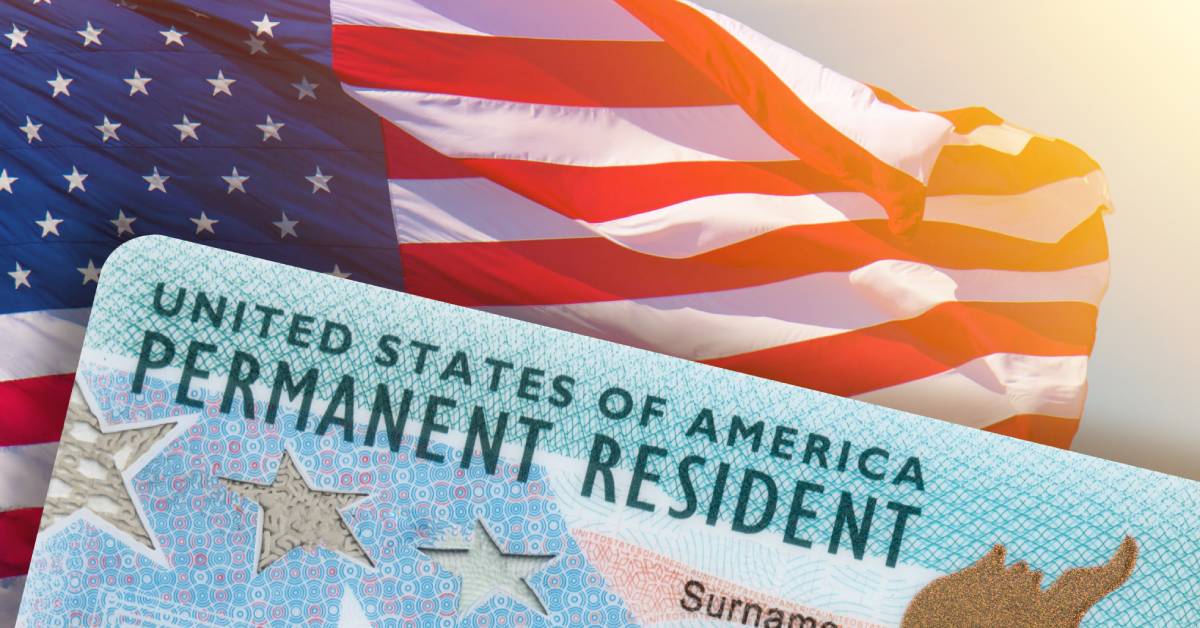 A close-up of a United States of America Permanent Resident Card with an American flag waving in the background.