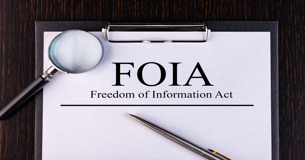 A pen and a magnifying glass lying on a white piece of paper that says "FOIA - Freedom of Information Act."