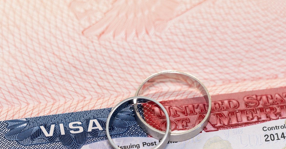 Two silver wedding bands sit on top of a blue and red United States Visa, with the control number showing 2014.