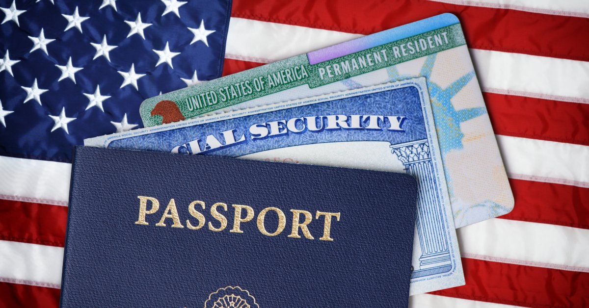 A United States passport with social security and permanent resident cards in it on top of the United States flag.