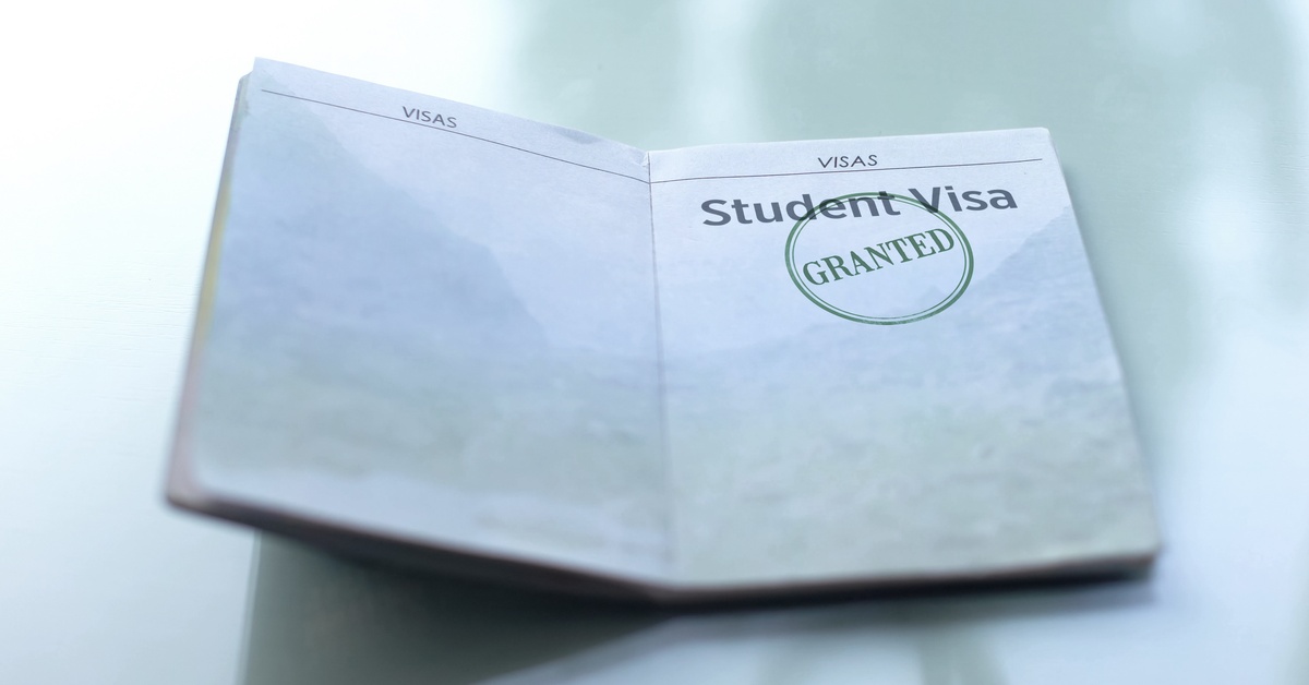 An open student visa that has a green "Granted" stamp sits on top of a sleek, reflective surface.