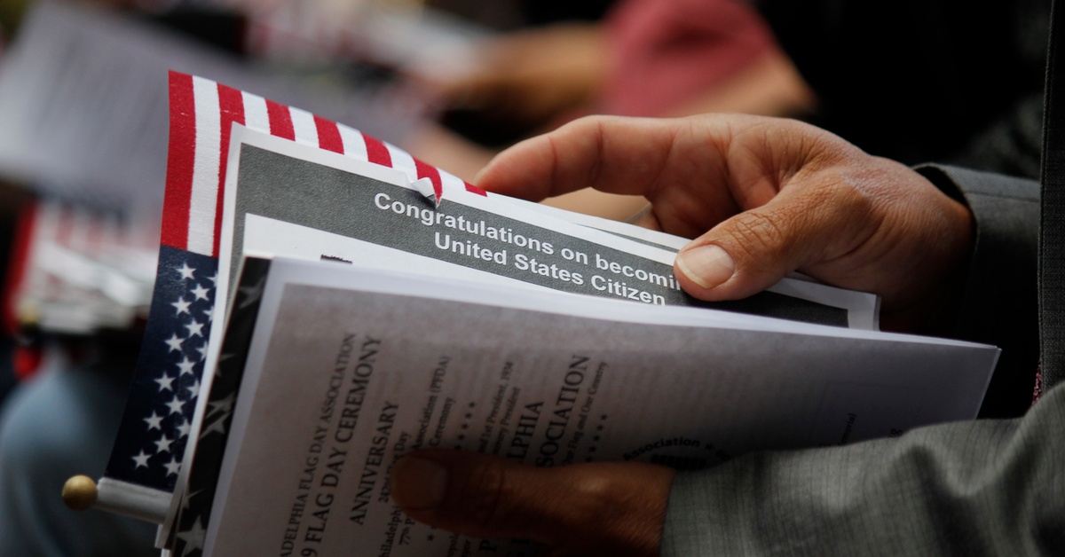 A person holds an array of documents that says "Congratulations on becoming a United States Citizen" and the U.S. Flag.