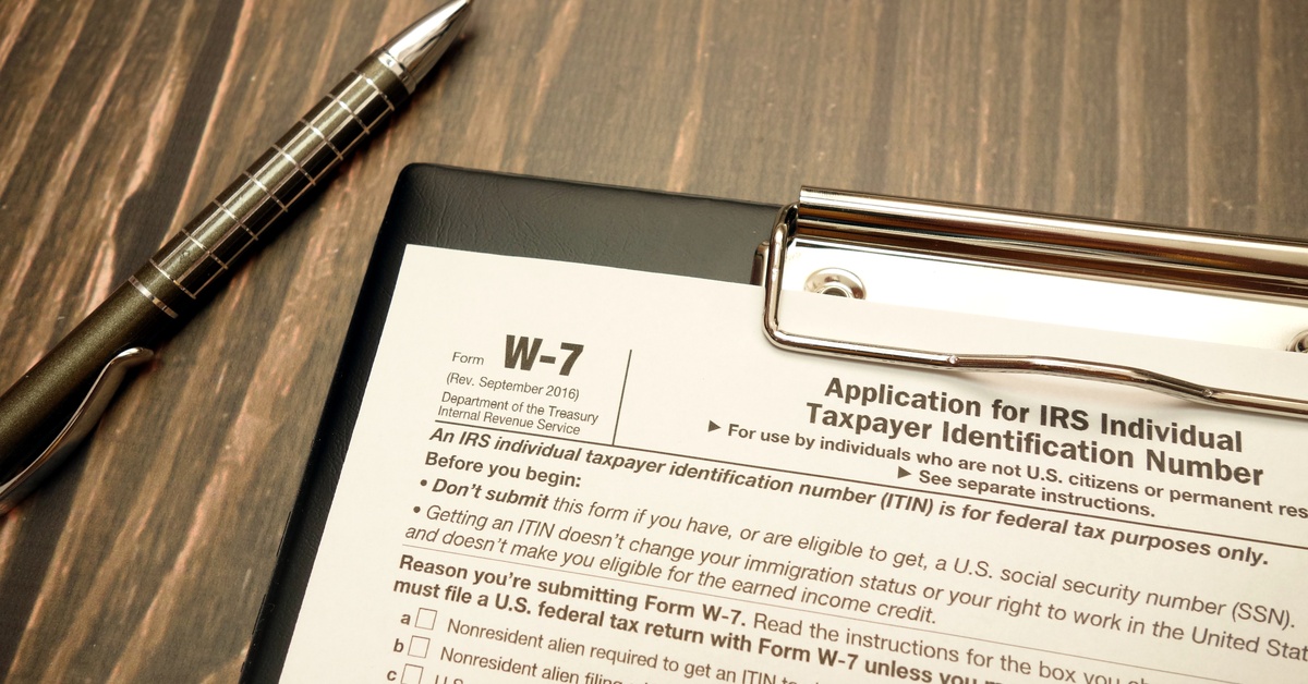 A black and silver pen sits next to a black clipboard with a form W-7, Individual Taxpayer Identification Number.