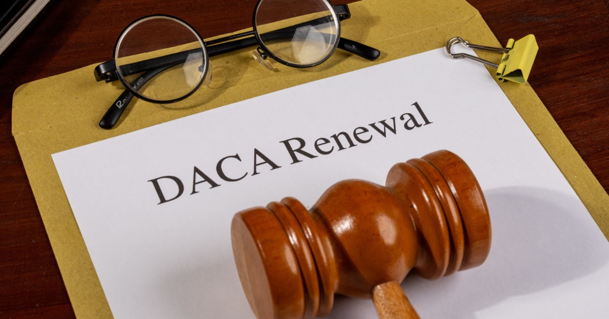 a DACA renewal document beside a wooden gavel and black pen on a desk, with printed form text visible.
