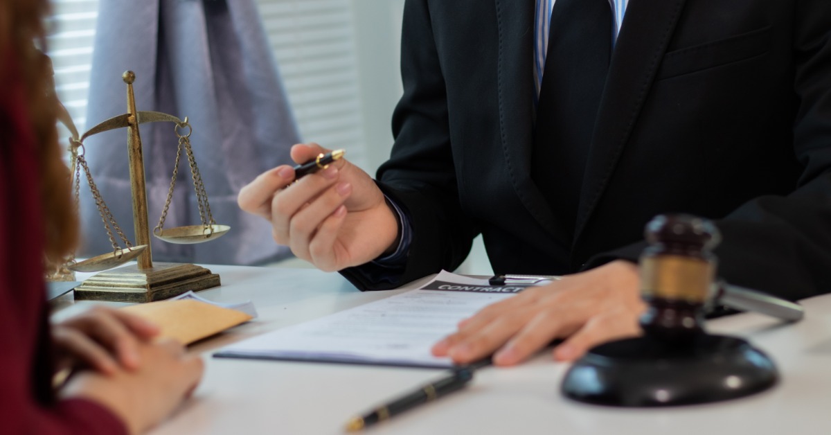 a wooden judge's gavel resting on a desk near legal paperwork, with a softly blurred office background.