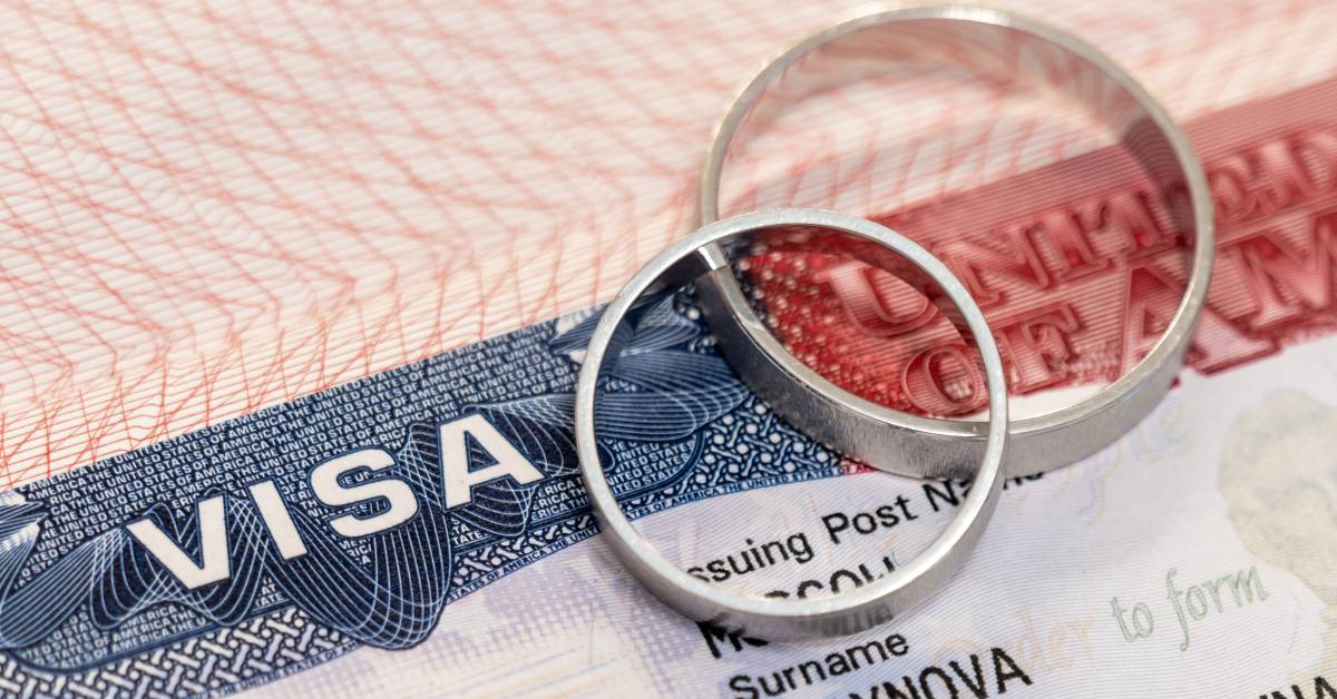 Two metal rings resting on a passport page with a blue visa label and red document text in close view.