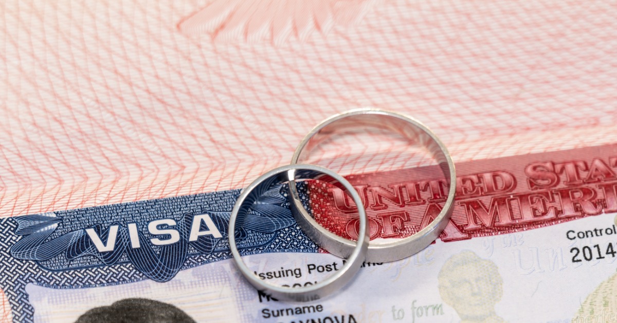 two rings resting on a United States visa document with red and blue printed details and pale patterned areas.